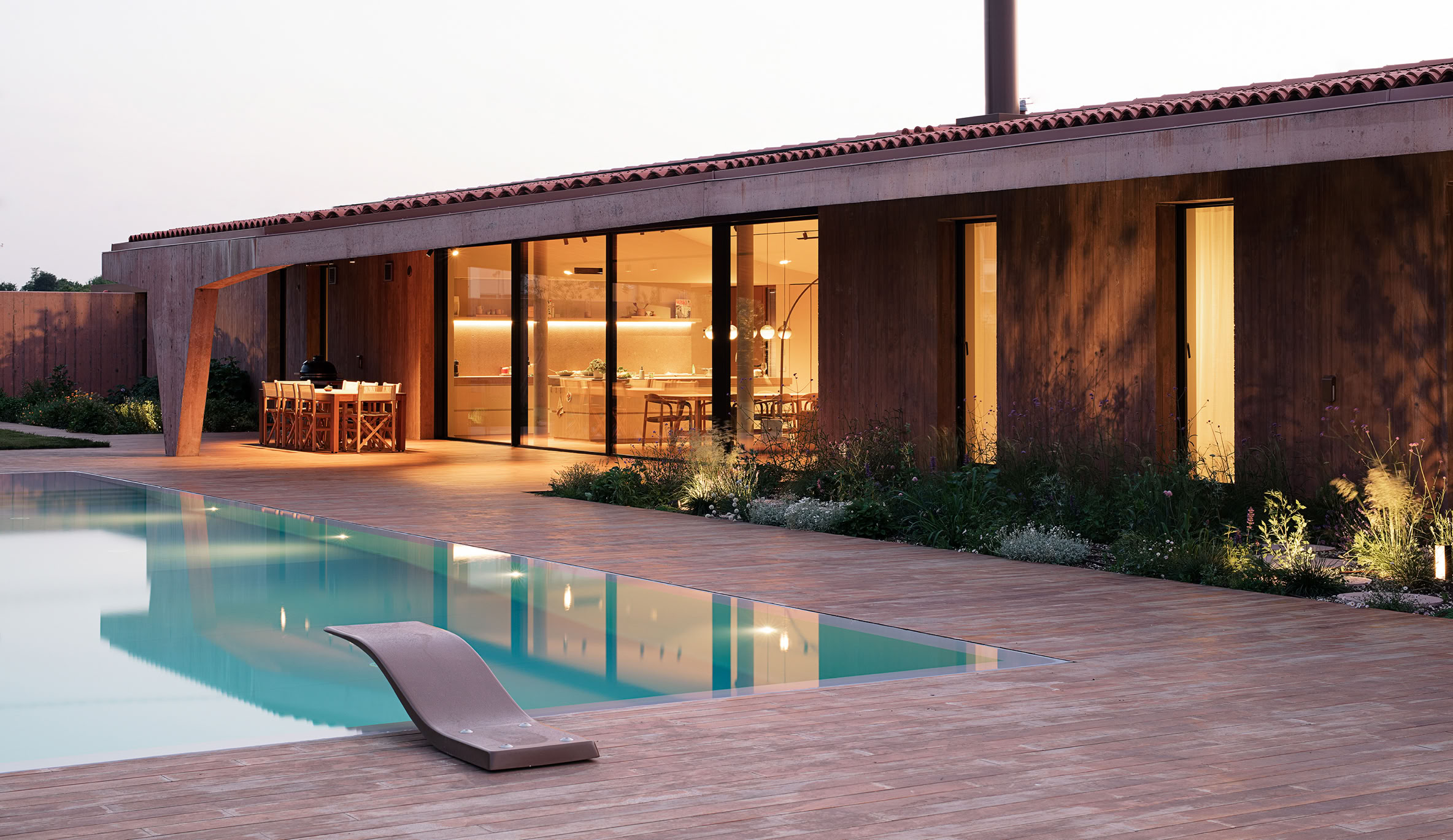 Vista al tramonto della villa con piscina a Vigodarzere in cui si accenta il legame tra esterno ed interno dell'abitazione. 