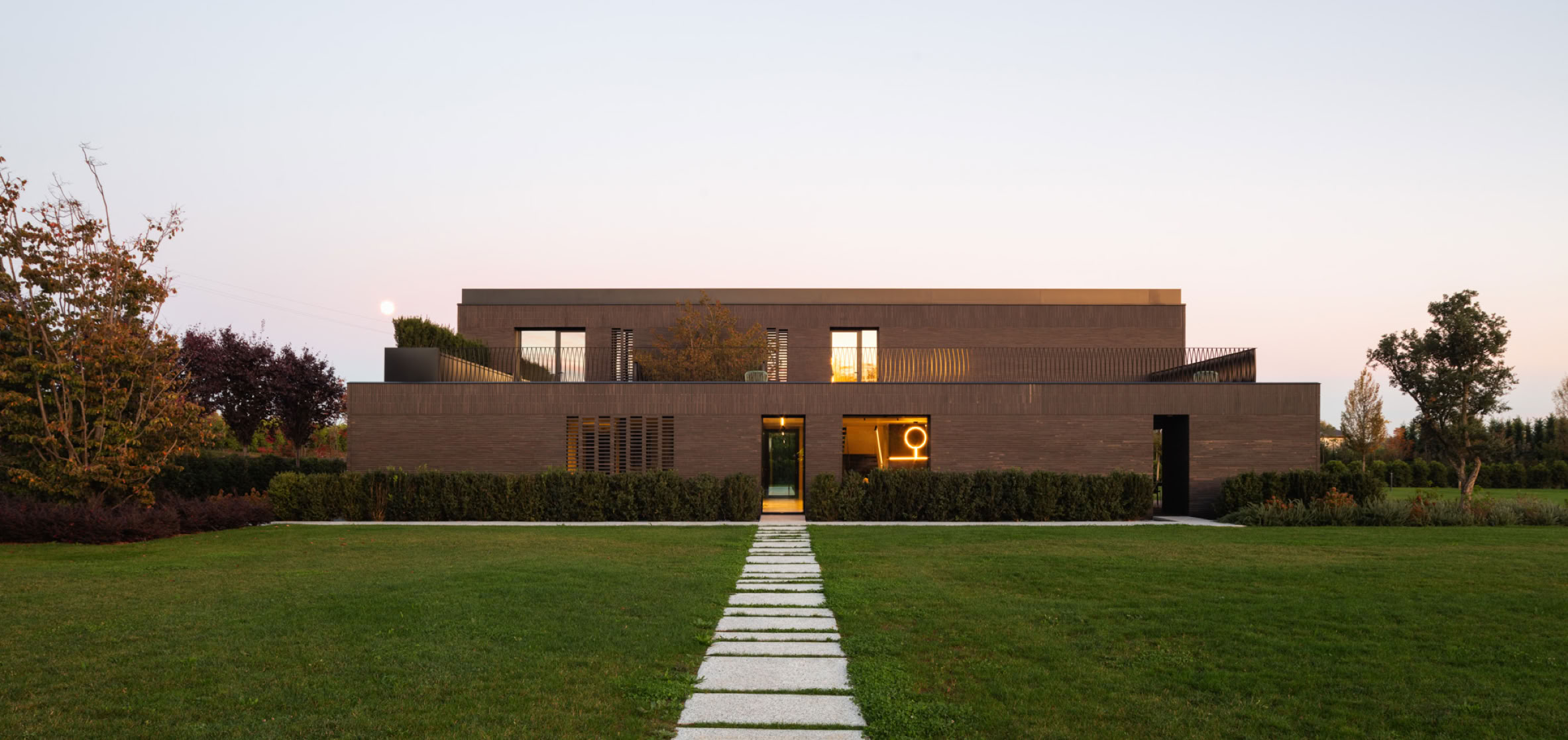 Villa in mattoni su due piani con ampie vetrate e terrazza panoramica: un progetto di architettura contemporanea raffinata e immersa nel paesaggio.