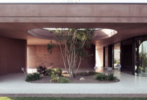 Le curve morbide della villa firmata da MIDE architetti accolgono al loro interno arbusti e alberi che dialogano con la matericità del calcestruzzo.