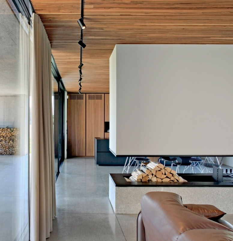 Open-space della zona giorno con cucina e soggiorno, orientato a sud e collegato al portico, che amplia lo spazio abitativo verso il verde.