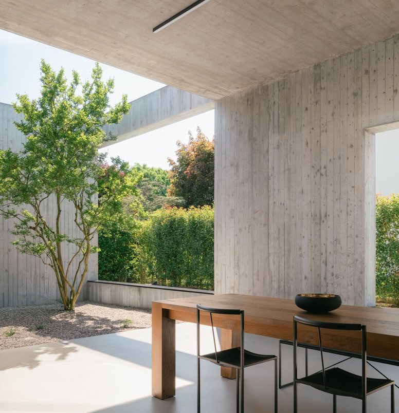 Contemporary single-family house designed by MIDE architetti, blending exposed concrete and natural wood. Open-plan living, central patio, and seamless connection with nature and garden.