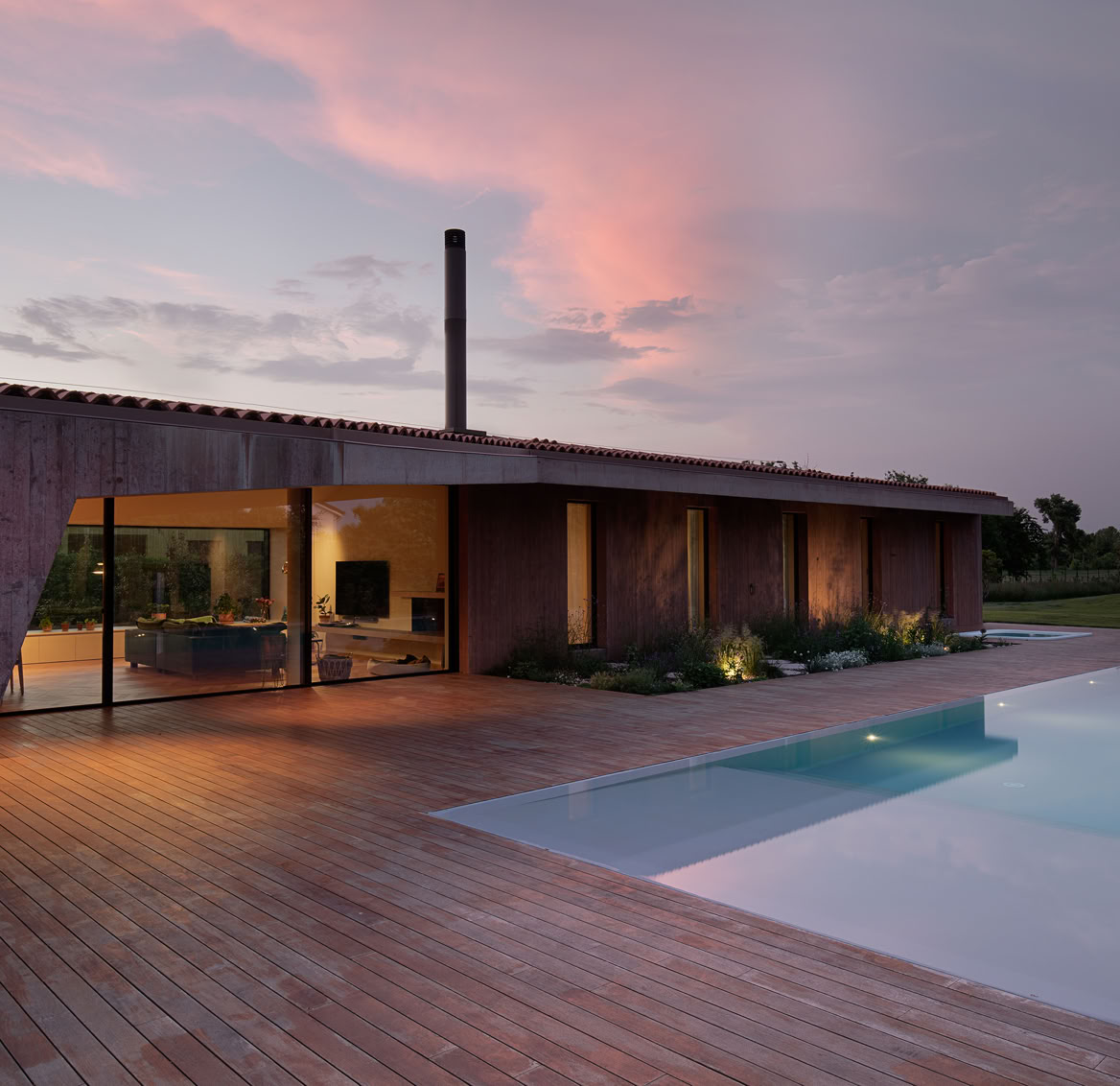 Vista al tramonto della villa con piscina a Vigodarzere in cui si accenta il legame tra esterno ed interno dell'abitazione. 