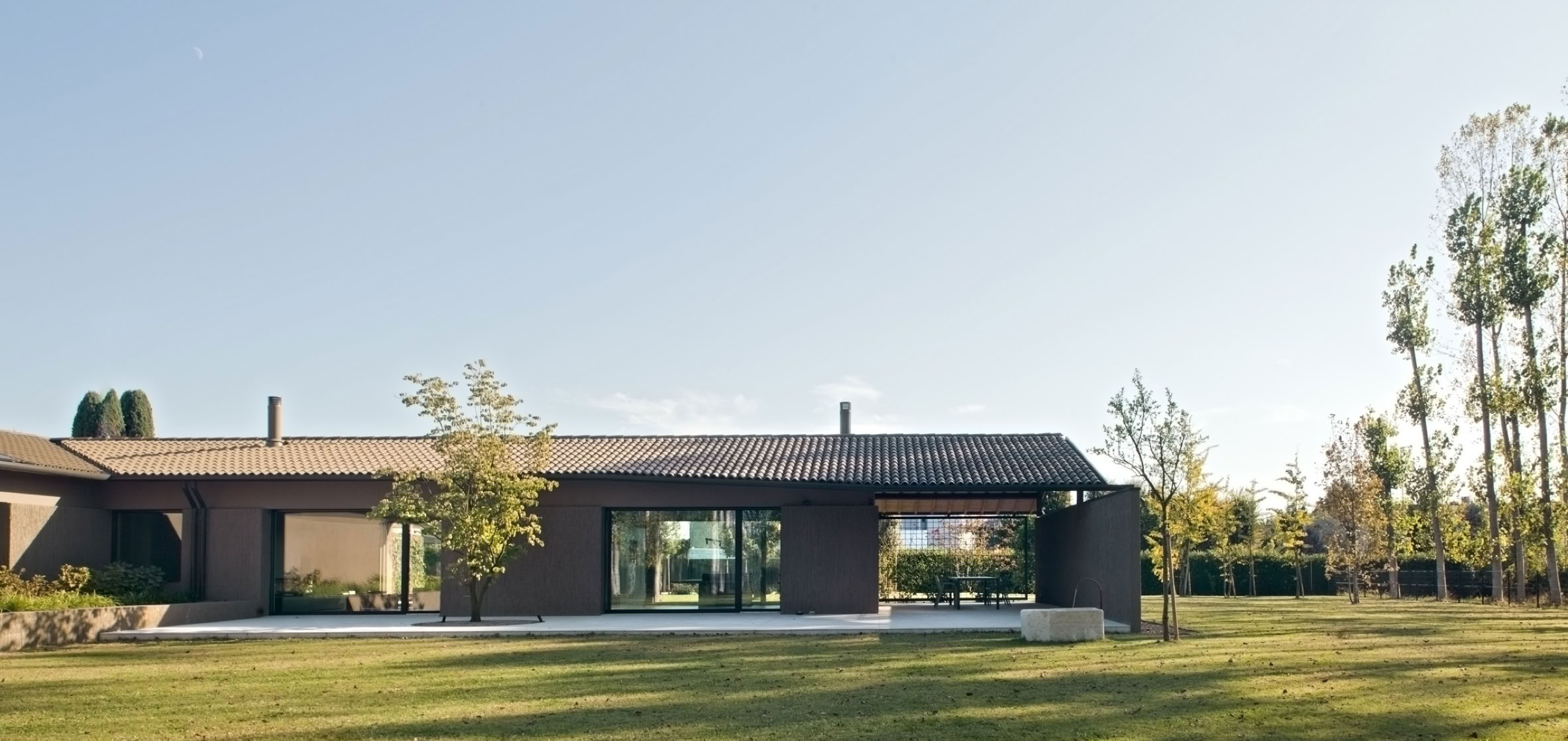 Contemporary villa in Noale reinterpreting Venetian rural architecture through natural light, tactile materials and landscape integration.