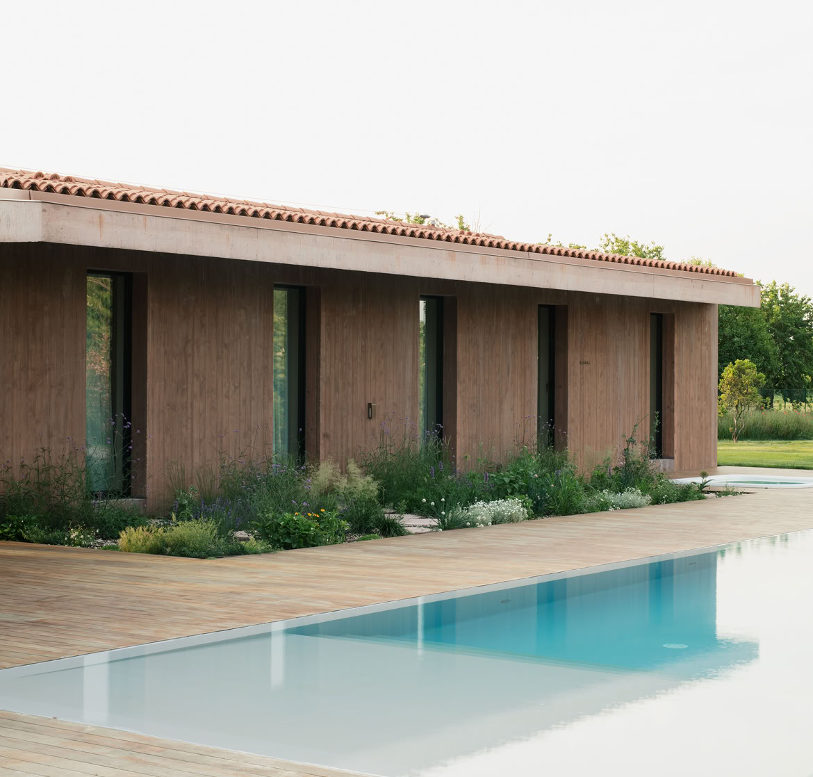 Propsetto della villa con aperture strette e lunghe per permettere la privacy alla zona notte dell'abitazone. Delicate piante ornamentali aumentano la sensazione di discrezione ricercata.