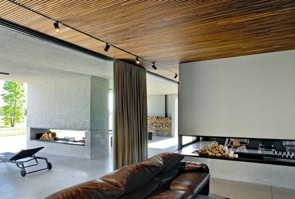 Open-space della zona giorno con cucina e soggiorno, orientato a sud e collegato al portico, che amplia lo spazio abitativo verso il verde.