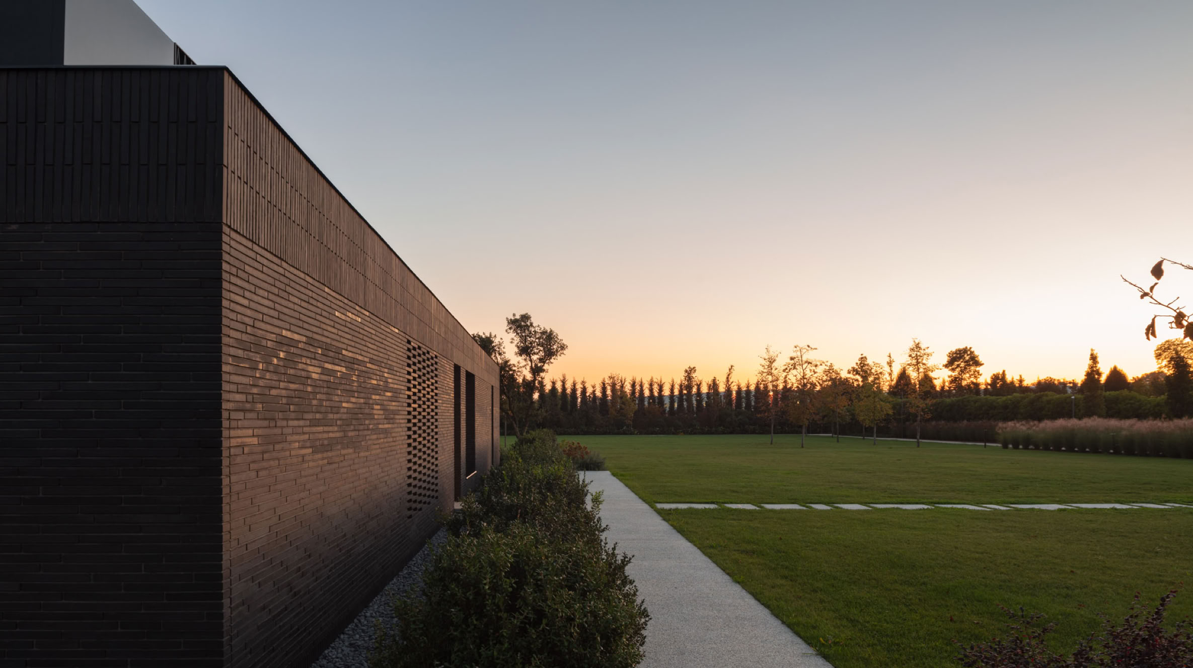 Brick-clad exterior at sunset of the villa set within the park, designed in Veneto by MIDE architetti.