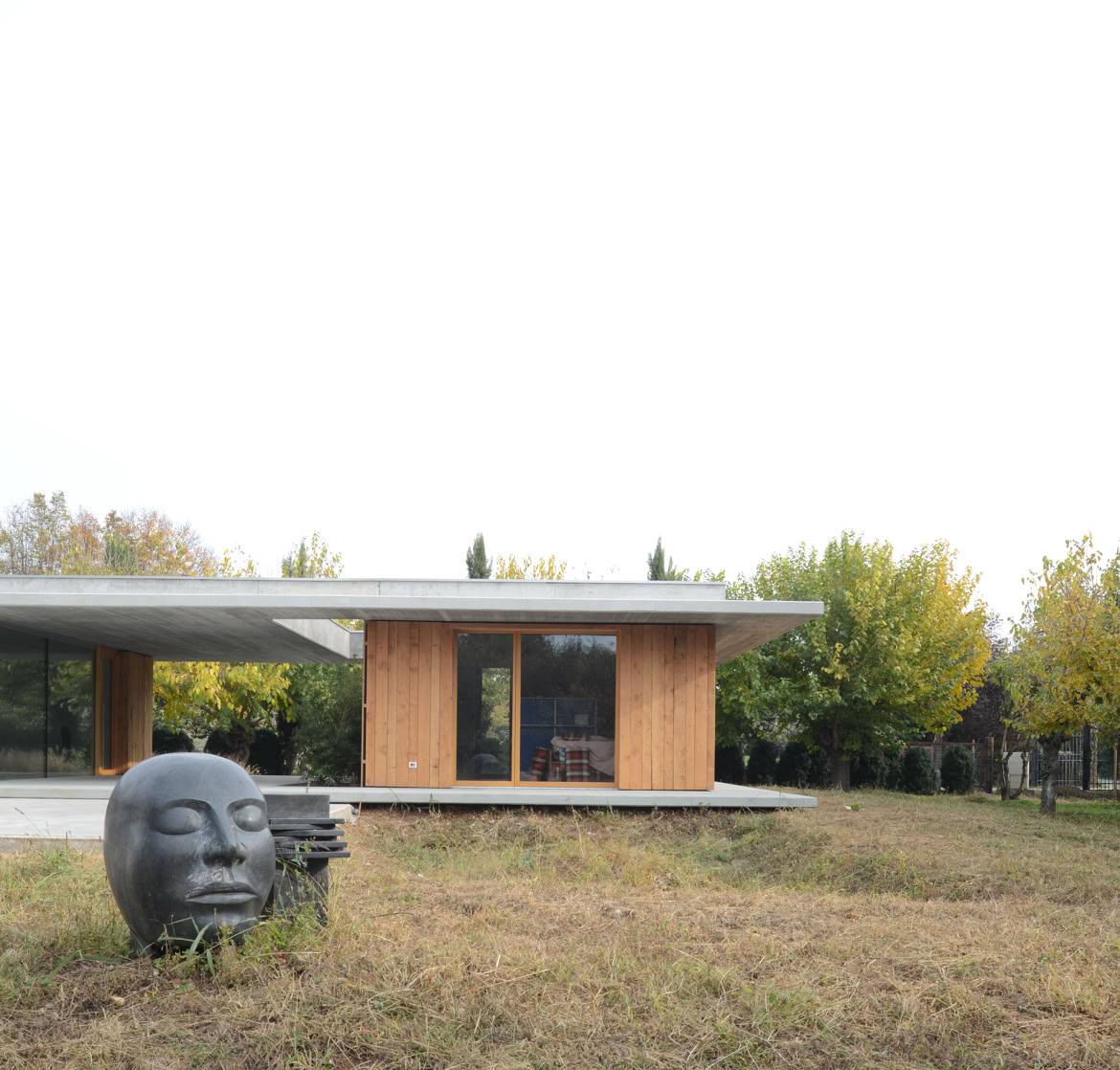 Casa moderna immersa nel parco con volumi semplici e ampie aperture vetrate che mettono in dialogo interno ed esterno.