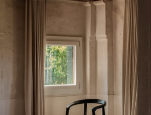 Pavimenti in resina neutra, travi lignee scure e pezzi iconici di design italiano creano un equilibrio elegante tra passato e presente.