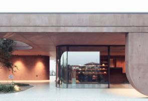 Spazio dedicato al relax, immerso nella quiete dell'ampio portico. Le grandi aperture lasciano entrare la luce e il verde, creando un ambiente intimo e contemplativo, in continuità con il paesaggio vegetale.