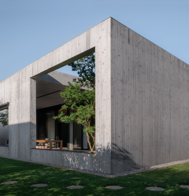 Contemporary single-family house designed by MIDE architetti, blending exposed concrete and natural wood. Open-plan living, central patio, and seamless connection with nature and garden.